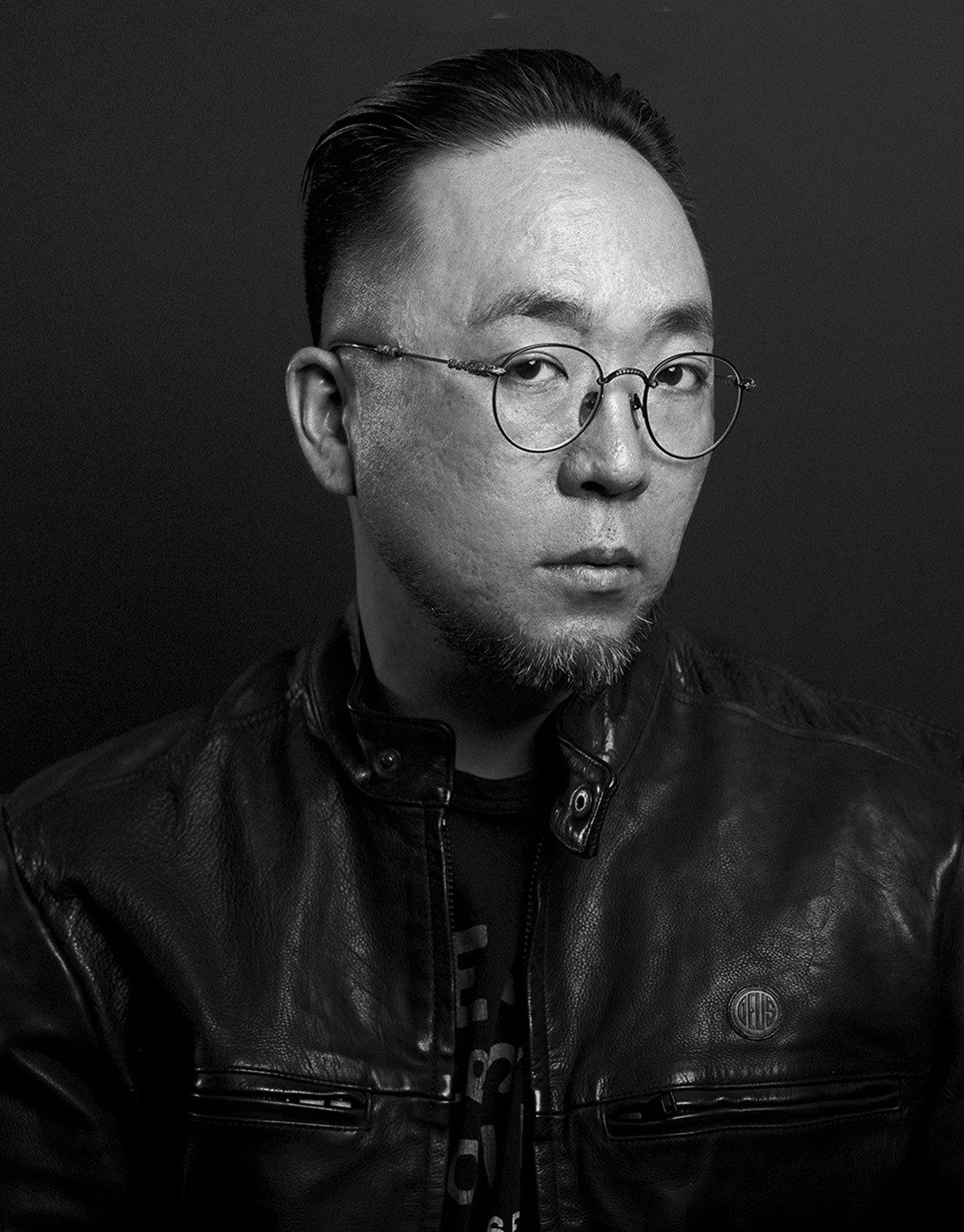 안경과 가죽 재킷을 착용한 인물의 흑백 포트레이트